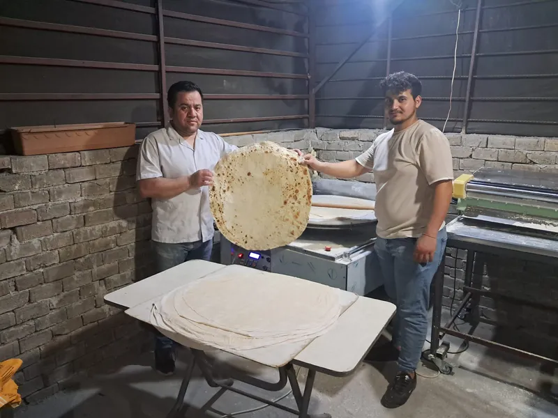 Hatay Payas’ta makineden çıkan yufkayı birlikte tutan iki kişi