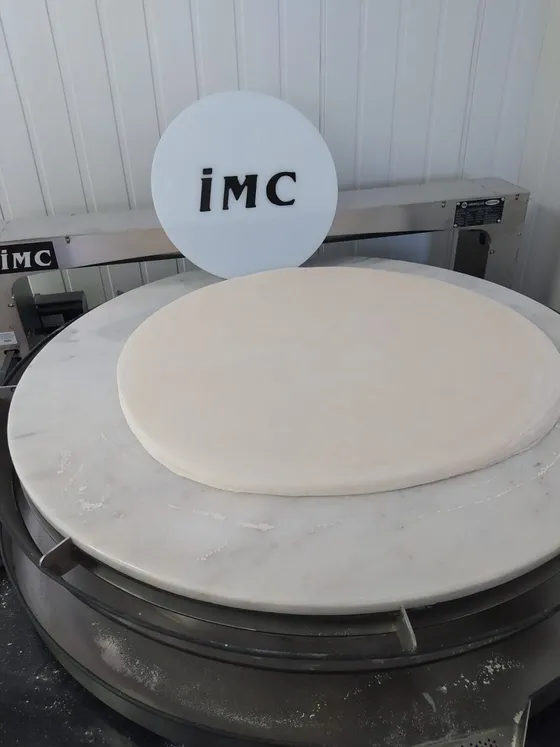 IMC Premium yufka açma makinesinin mermer tablasında açılmış hamur ve IMC logosu